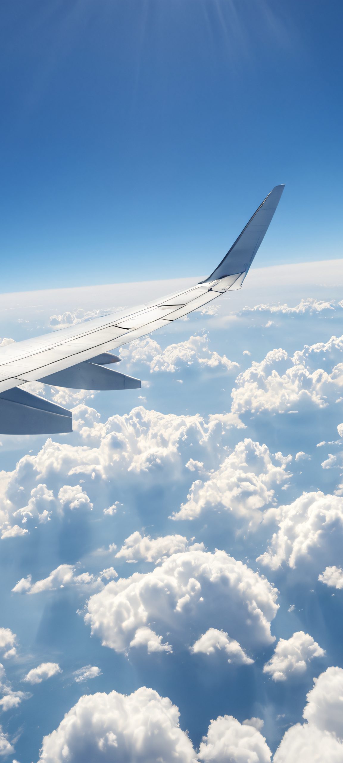 A breathtaking airplane window view with cloudy skies and soft daylight, perfect for iPhone/Android homescreens.